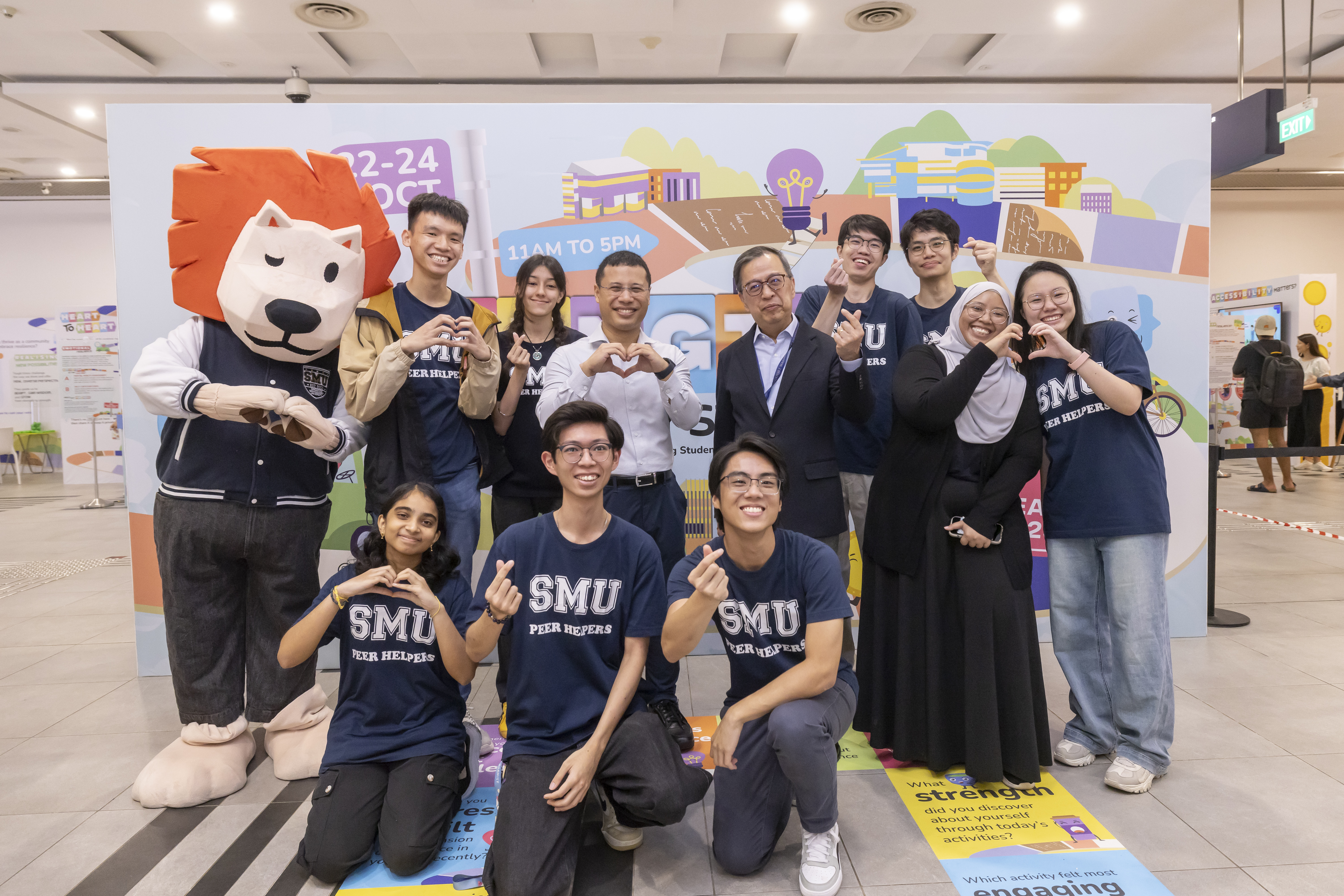 Minister for Education and Minister-in-Charge of Social Services Integration Mr Desmond Lee, SMU Provost Prof Alan Chan, SMU Peer Helpers, and SMOO SMOO strike heart poses to celebrate Mental Health Week 2025.