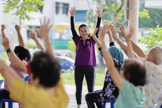 A volunteer helping to lead exercises for seniors outside an active ageing centre run by Allkin Singapore. ST PHOTO: GIN TAY